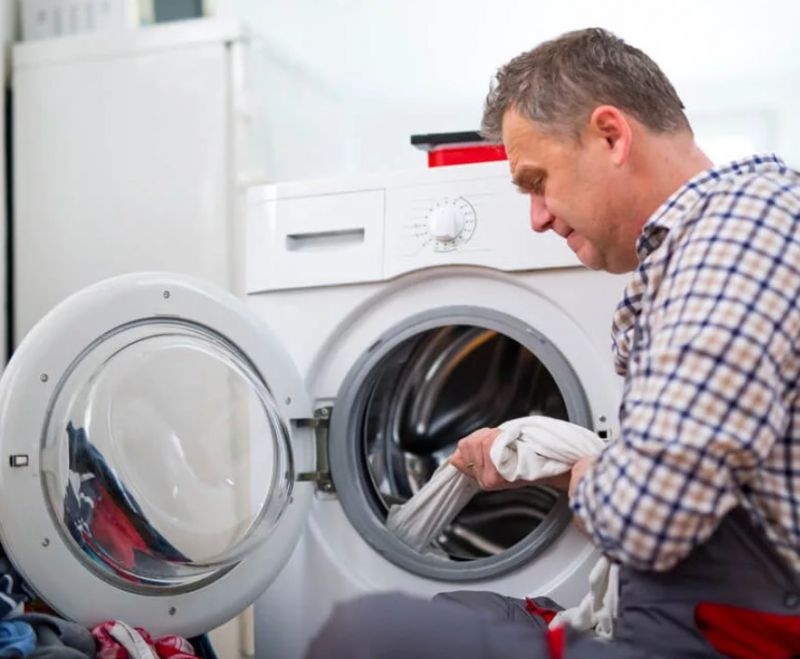 Мужчина вытягивает белье из стиральной машины
